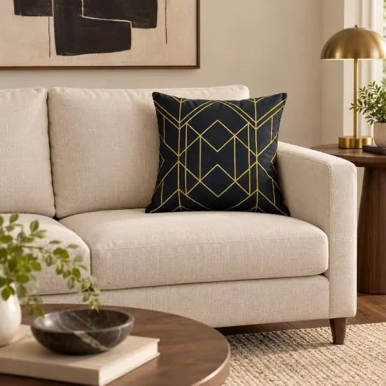 Față de pernă decorativă cu model geometric auriu pe fond negru pe canapea